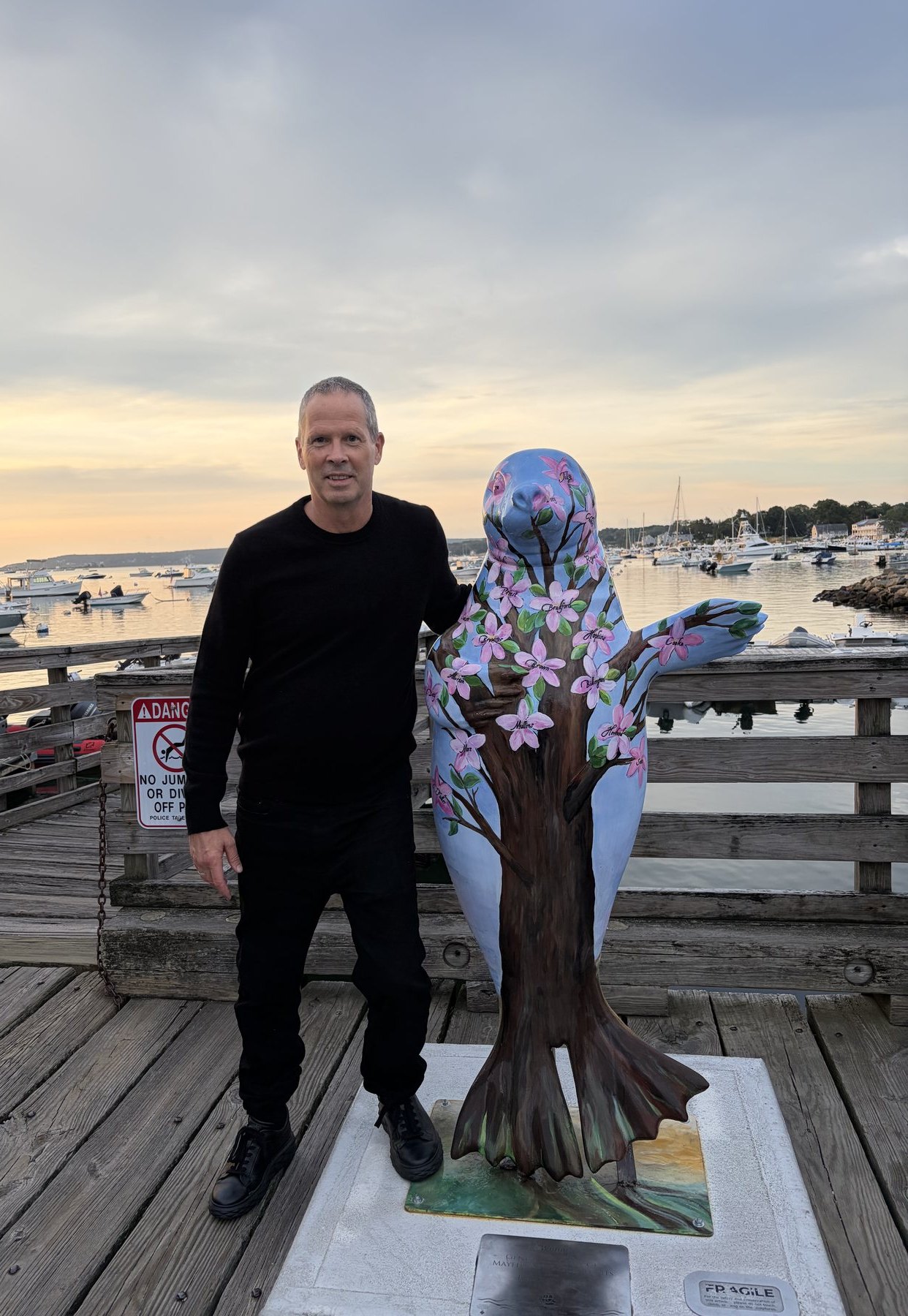 Charlie Hough on a New England harbor dock at sunset, dressed in black — calm, confident, campaign-ready.